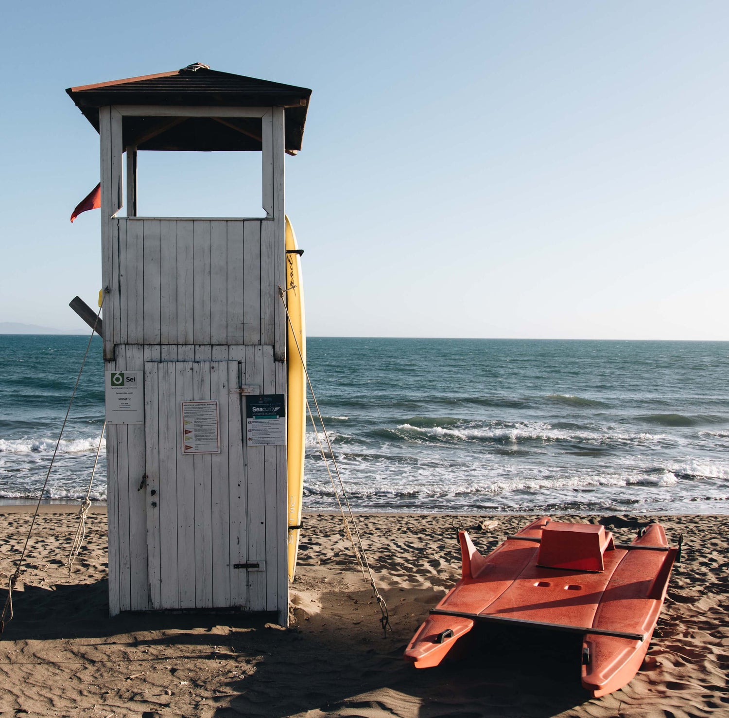 Lifeguard tower and orange boat on a sandy beach with ocean in the background